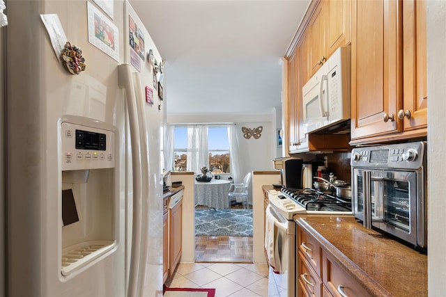 kitchen with white appliances, stone countertops, and light tile patterned flooring