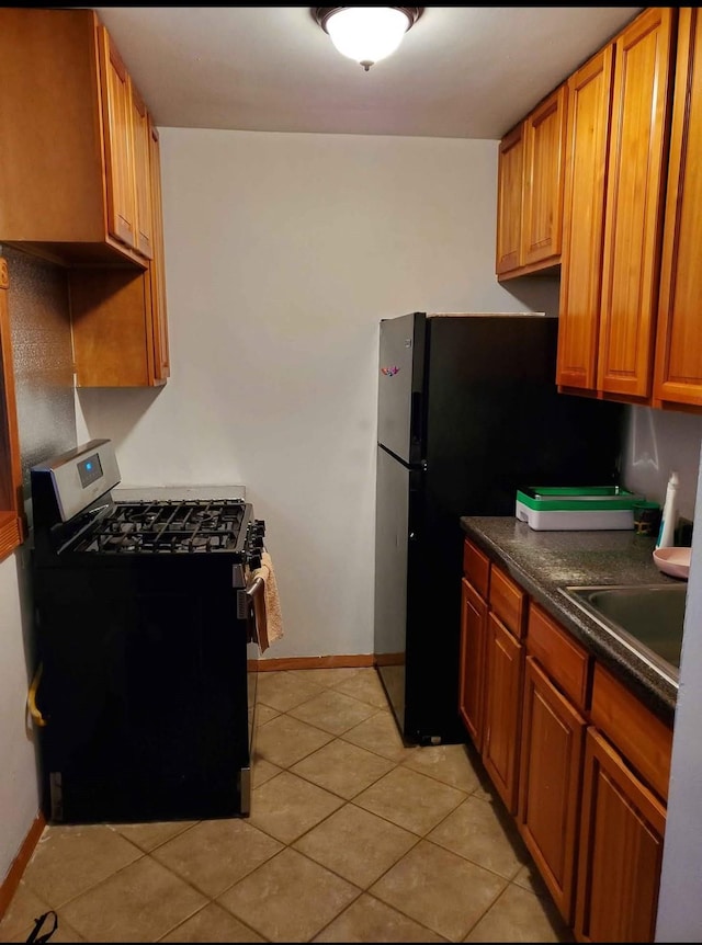 kitchen with black range with gas stovetop, sink, and light tile patterned flooring