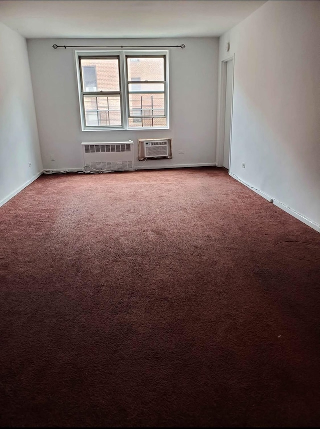 spare room with carpet flooring, an AC wall unit, and radiator