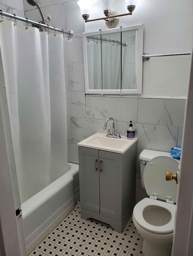 full bathroom with tile patterned floors, toilet, shower / tub combo with curtain, vanity, and tile walls