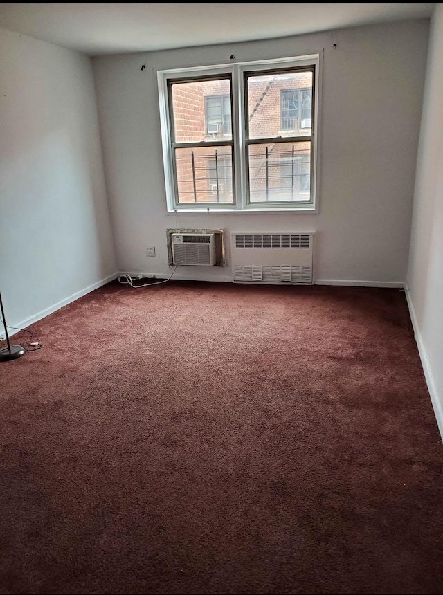 spare room featuring carpet flooring, radiator heating unit, and an AC wall unit