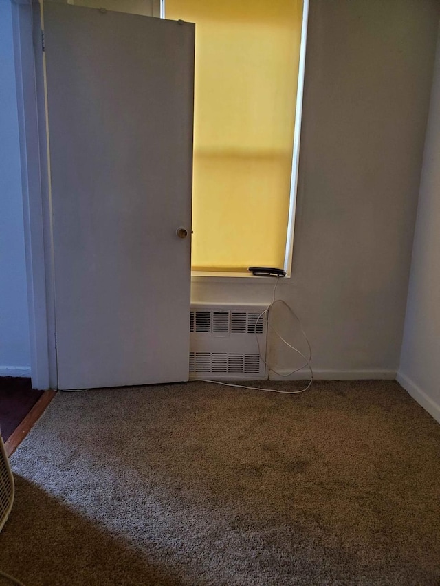 carpeted spare room featuring radiator