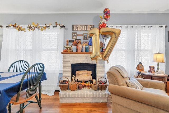 dining room featuring hardwood / wood-style floors, crown molding, a wealth of natural light, and a brick fireplace