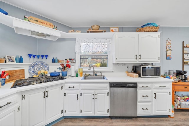 kitchen with white cabinets, crown molding, sink, light hardwood / wood-style flooring, and appliances with stainless steel finishes