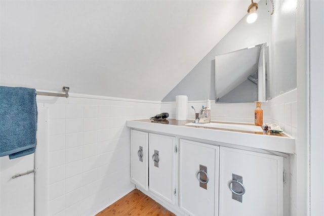 bathroom with vanity, hardwood / wood-style flooring, tile walls, and lofted ceiling