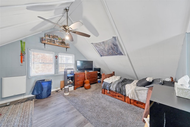 bedroom with ceiling fan, light hardwood / wood-style flooring, vaulted ceiling, and radiator heating unit