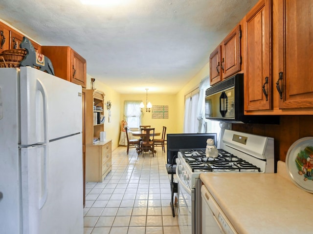 kitchen featuring light tile patterned flooring, white appliances, hanging light fixtures, and an inviting chandelier