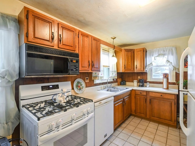 kitchen featuring light tile patterned floors, white appliances, hanging light fixtures, and sink