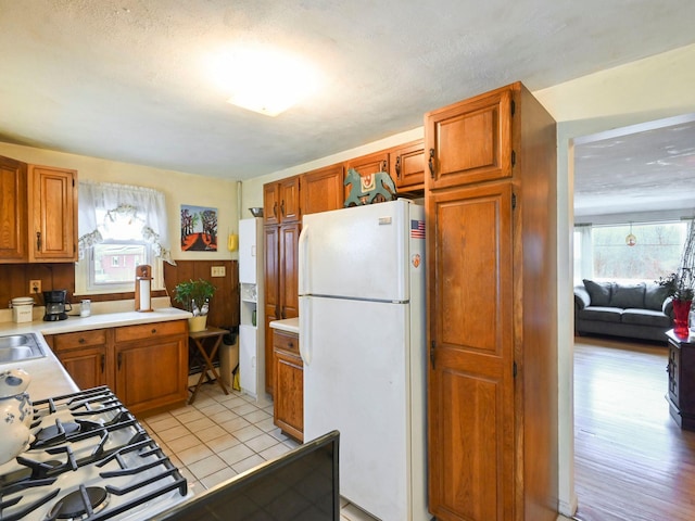 kitchen featuring plenty of natural light, white fridge, light tile patterned flooring, and sink