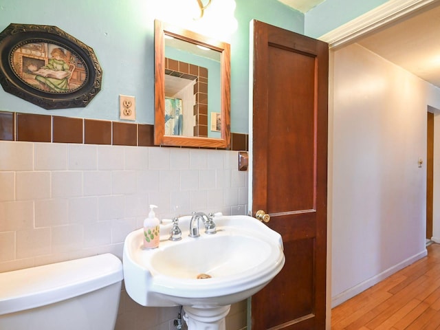 bathroom with backsplash, toilet, tile walls, and sink