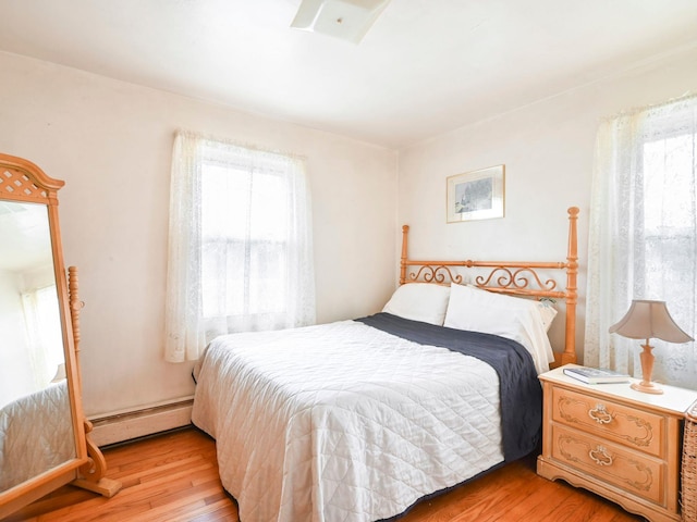 bedroom featuring light hardwood / wood-style floors and a baseboard heating unit