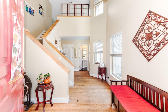foyer featuring wood finished floors, baseboards, a wealth of natural light, and a towering ceiling