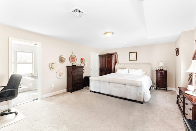 bedroom with baseboards, visible vents, light carpet, and ensuite bathroom