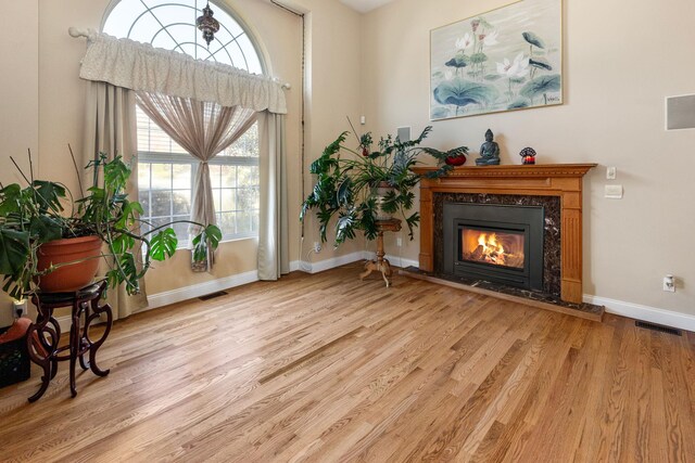 living area with baseboards, visible vents, light wood finished floors, and a fireplace