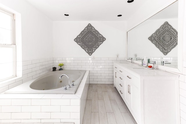 bathroom with double vanity, a sink, a healthy amount of sunlight, and a jetted tub