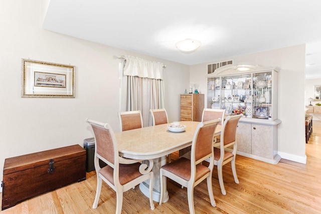 dining space featuring baseboards, light wood-style flooring, and visible vents