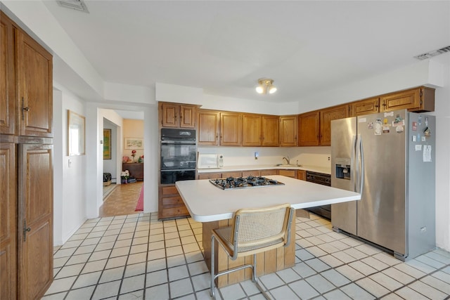 kitchen with light tile patterned floors, a kitchen bar, a kitchen island, appliances with stainless steel finishes, and sink