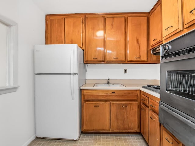 kitchen featuring white fridge, stainless steel gas cooktop, and sink