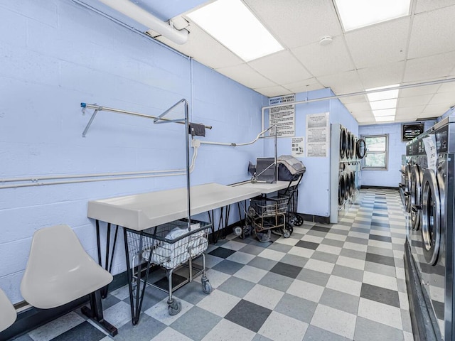 misc room featuring washing machine and clothes dryer, a paneled ceiling, and stacked washing maching and dryer