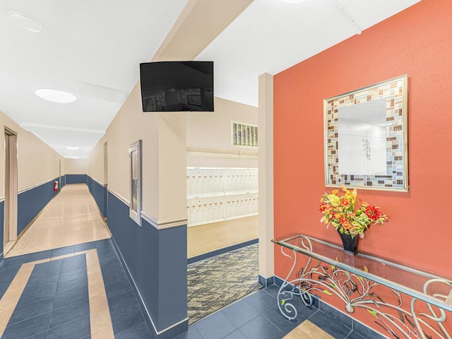 corridor with dark tile patterned flooring and a mail area