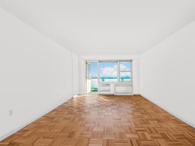 spare room featuring radiator heating unit and light parquet floors