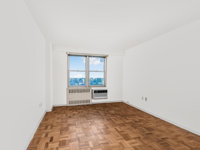 spare room featuring parquet flooring, radiator heating unit, and a wall mounted air conditioner