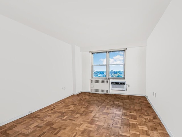 spare room with a wall mounted AC, light parquet flooring, and radiator