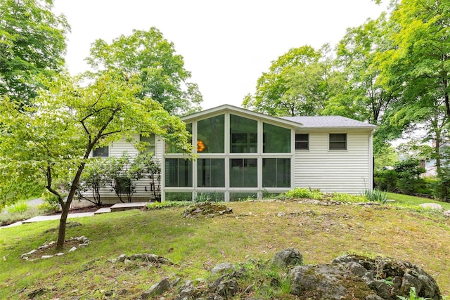 rear view of house with a sunroom and a lawn