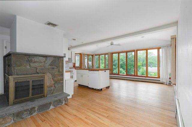 unfurnished living room featuring ceiling fan, a baseboard radiator, a stone fireplace, beamed ceiling, and light hardwood / wood-style floors