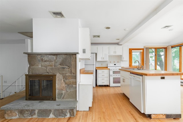 kitchen featuring light hardwood / wood-style flooring, backsplash, white appliances, a fireplace, and white cabinets