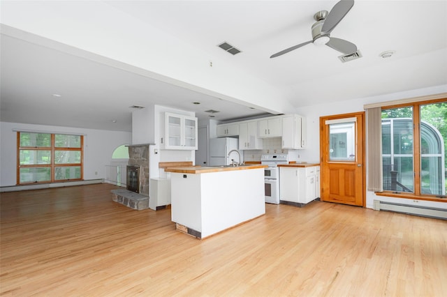 kitchen featuring light wood-type flooring, white appliances, a kitchen island, a baseboard heating unit, and white cabinetry