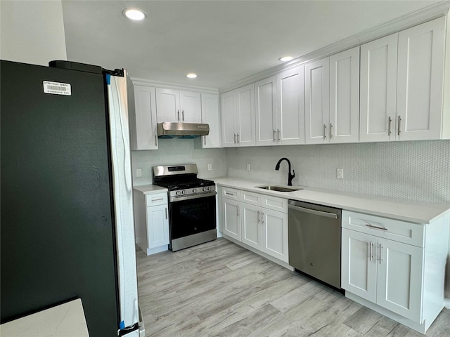 kitchen with sink, light hardwood / wood-style flooring, appliances with stainless steel finishes, tasteful backsplash, and white cabinetry