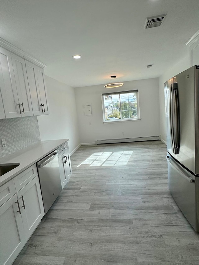 kitchen featuring white cabinets, appliances with stainless steel finishes, light hardwood / wood-style floors, and a baseboard radiator