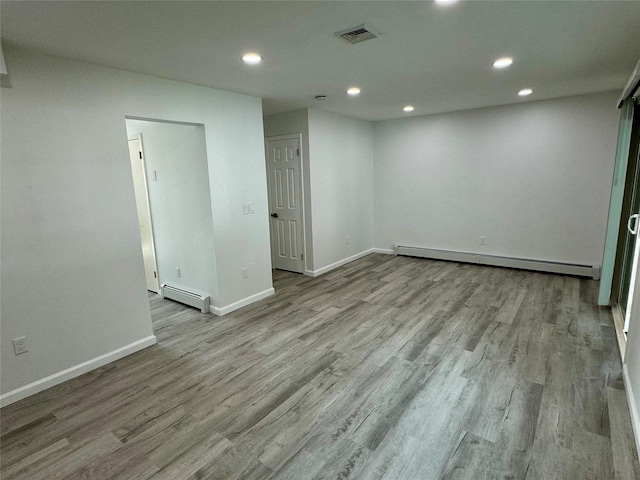 spare room featuring a baseboard radiator and light hardwood / wood-style floors