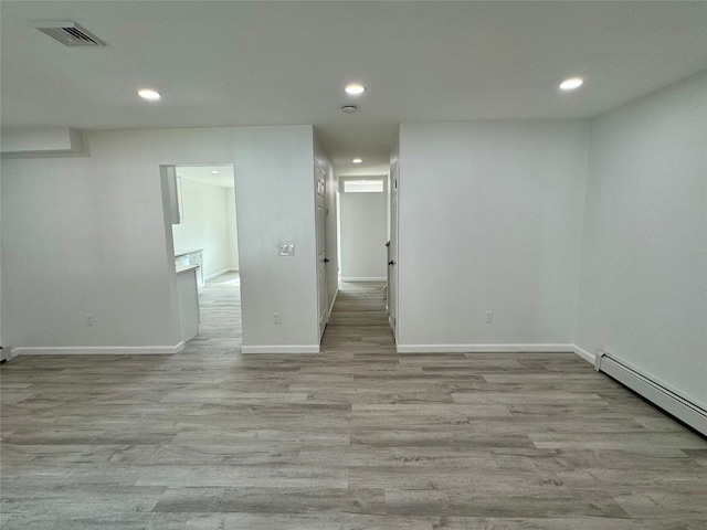 empty room with light wood-type flooring and a baseboard heating unit