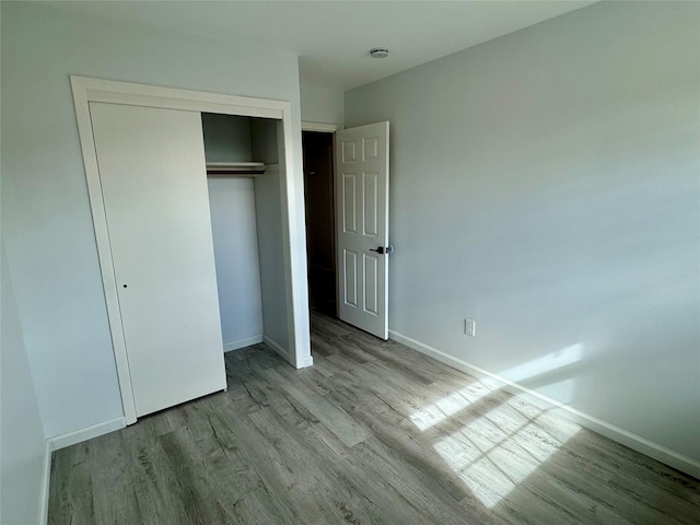 unfurnished bedroom with light wood-type flooring and a closet