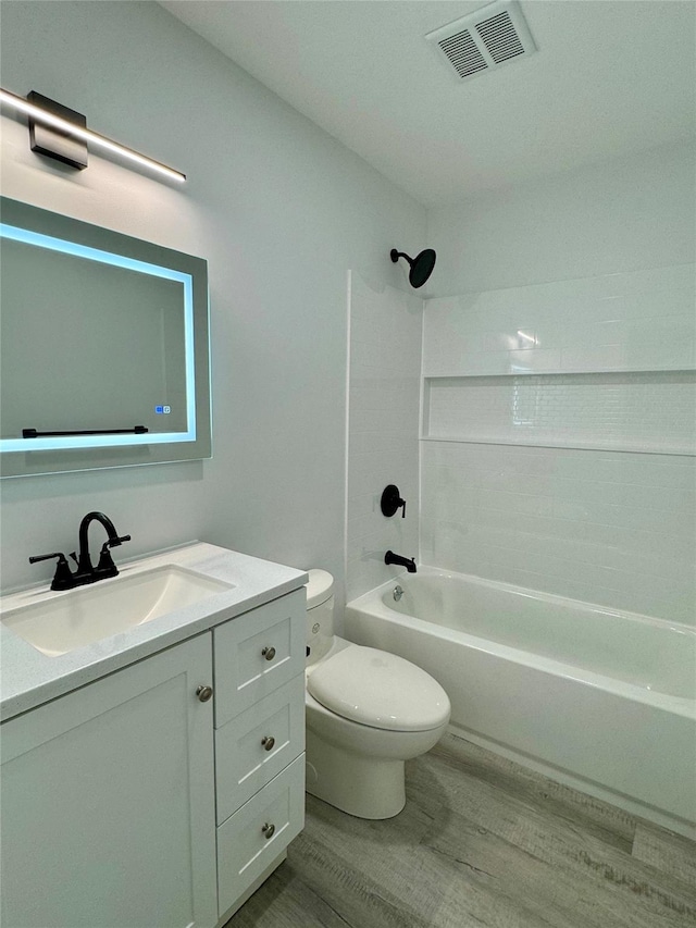 full bathroom with hardwood / wood-style floors, vanity, toilet, and tiled shower / bath