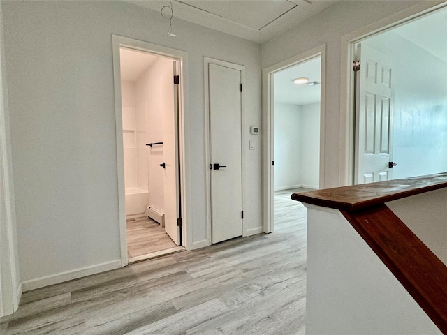 hall with light hardwood / wood-style floors and a baseboard heating unit