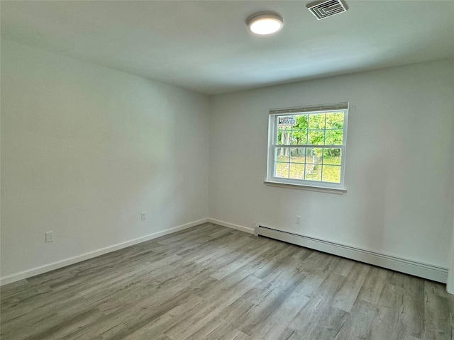 unfurnished room with light hardwood / wood-style flooring and baseboard heating