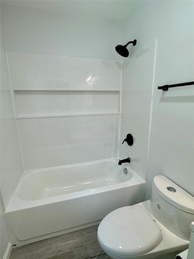 bathroom with hardwood / wood-style flooring, toilet, and tiled shower / bath