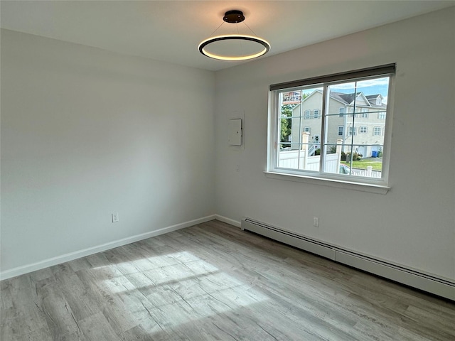 empty room featuring a baseboard radiator and light hardwood / wood-style flooring