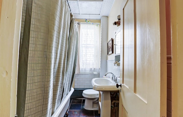 bathroom with toilet, tile patterned floors, tile walls, and sink