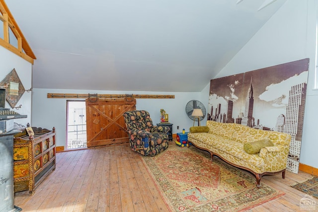 living room featuring a barn door, wood-type flooring, and lofted ceiling