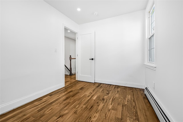 spare room featuring wood-type flooring and a baseboard heating unit