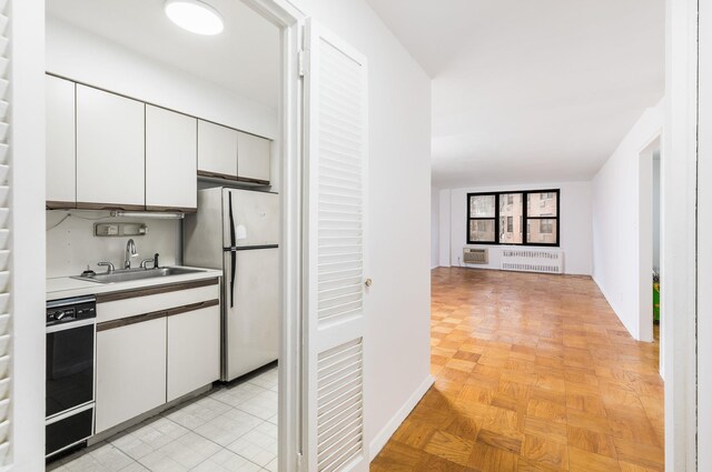 40 Brighton 1st Rd Unit 3J, Brooklyn, NY 11235 - kitchen featuring freestanding refrigerator, a sink, open floor plan, radiator, and white cabinetry
