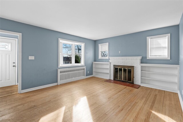 unfurnished living room with light hardwood / wood-style floors, a fireplace, and radiator