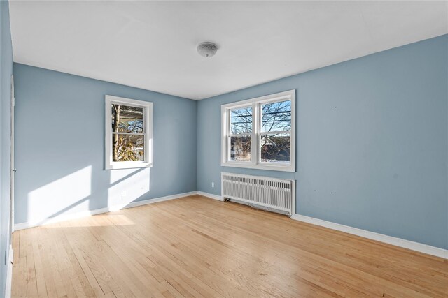 unfurnished room featuring light wood-type flooring and radiator