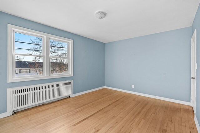 unfurnished room featuring radiator and light hardwood / wood-style floors