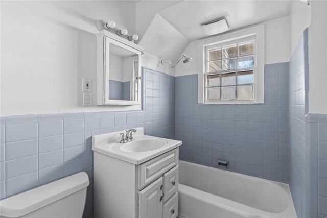 full bathroom featuring vanity, toilet, tile walls, and tiled shower / bath