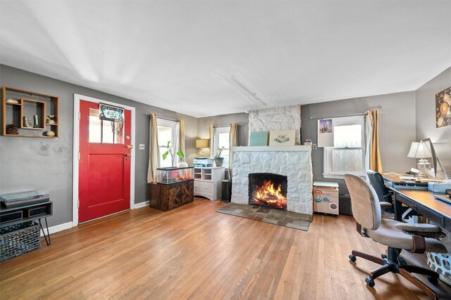 home office with hardwood / wood-style floors and a stone fireplace